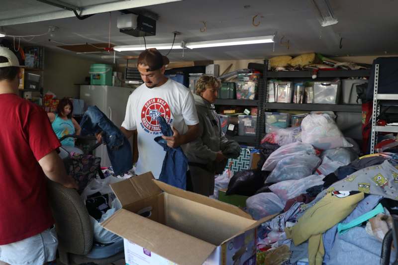 a group of people in a room with boxes and clothes