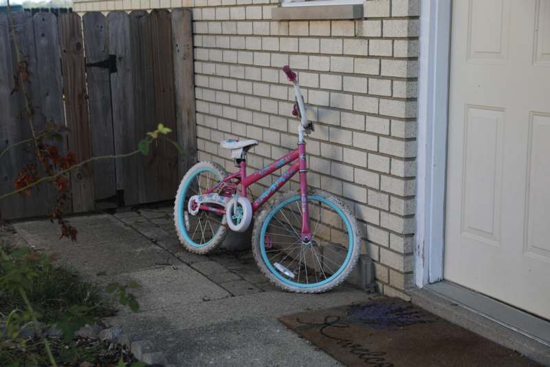 a pink bicycle leaning against a brick wall