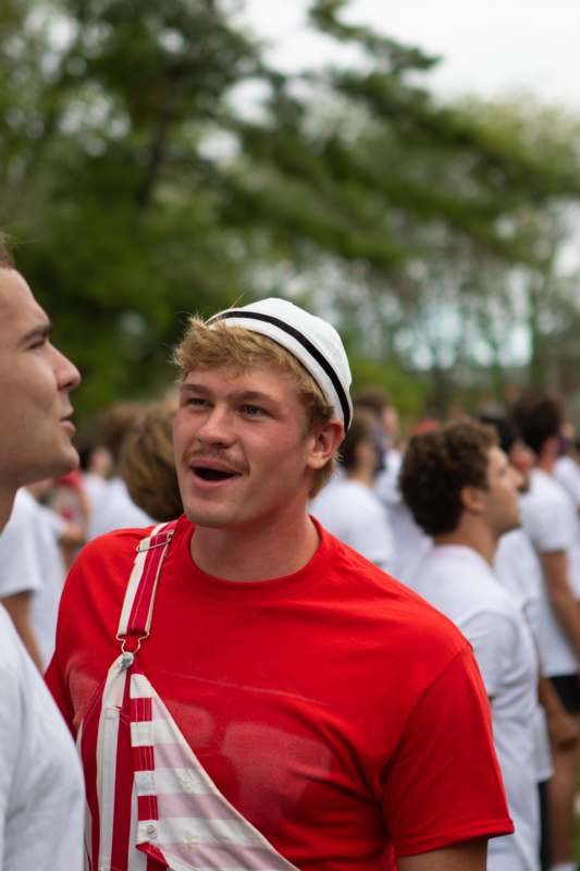 a man in a red shirt and white hat talking to another man