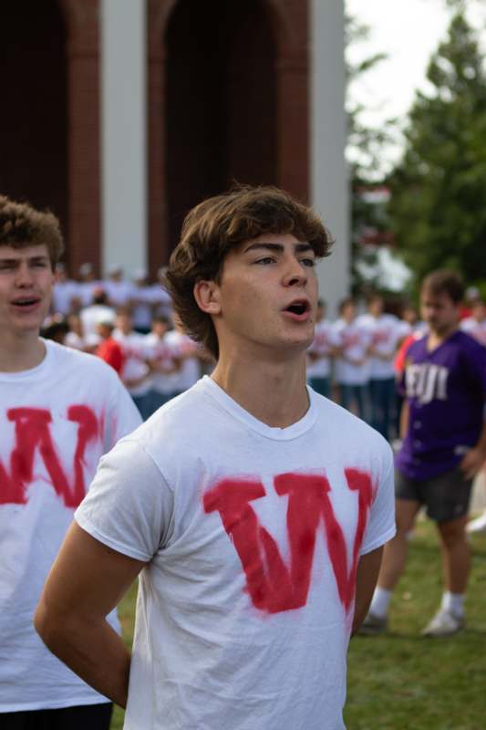 a group of men in white shirts with red letters on them