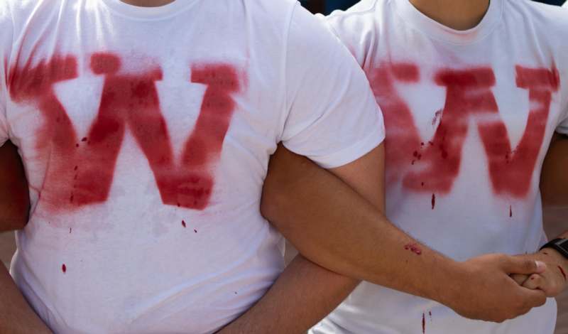 a pair of men wearing white shirts with red letters on them