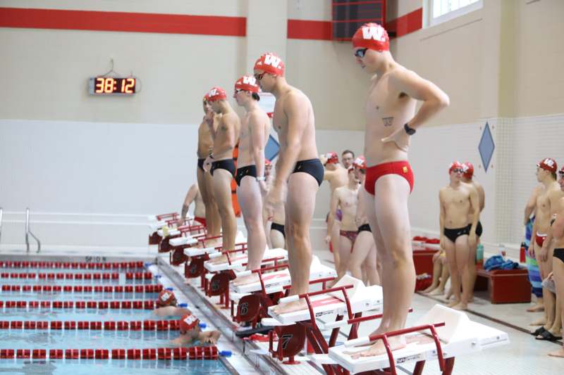 a group of people in swim suits standing on a swimming pool