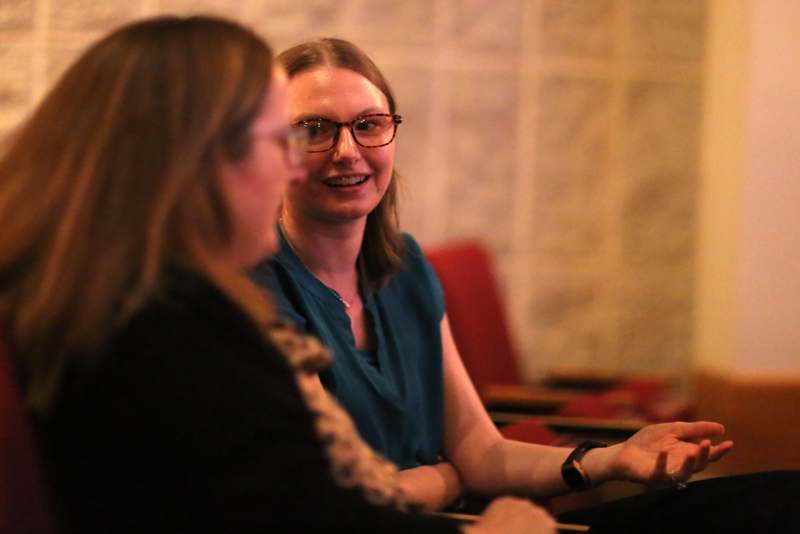 a woman sitting at a table with another woman in glasses