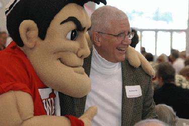 a man smiling at a person with a mascot