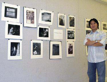a man standing next to a wall of photographs