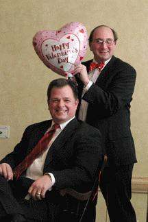 a couple of men in suits holding a heart shaped balloon
